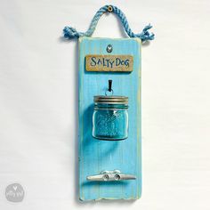 a blue sign with a mason jar hanging from it's side on a white wall