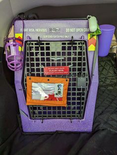 a purple dog carrier sitting on top of a black bed covered in blankets and other items