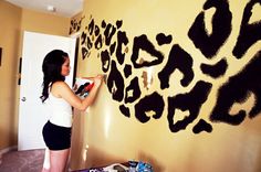 a woman is painting a wall with black and white animal prints on the walls in her bedroom