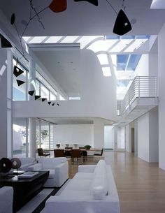 a living room filled with white furniture and lots of windows on top of it's walls