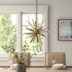 a dining room table is set with place settings for four and has a starburst chandelier hanging from the ceiling