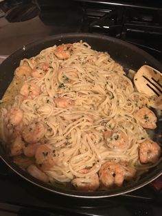 a pan filled with pasta and shrimp on top of a stove