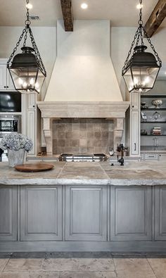 a large kitchen with two hanging lights over the stove and an island in front of it