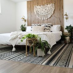 a bedroom with white bedding and plants on the wall