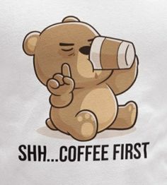 a brown teddy bear sitting on top of a white t - shirt that says shh coffee first