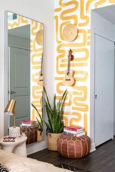 a living room with a guitar on the wall next to a potted plant and mirror