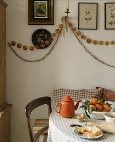 a dining room table with plates, cups and bowls on it next to pictures hanging on the wall