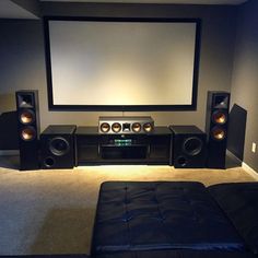 a home theater with speakers and a large screen on the wall in front of it