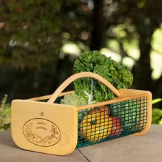 a basket filled with vegetables sitting on top of a cement floor next to trees and bushes