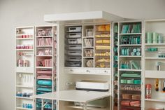 a sewing room with lots of crafting supplies on shelving units and desks