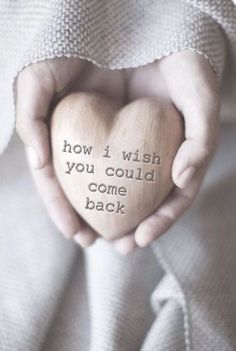 someone holding a wooden heart that says how i wish you could come back