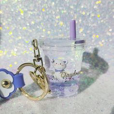 a cup with a keychain attached to it sitting on a glittery surface