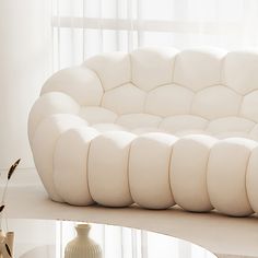 a white couch sitting on top of a table next to a vase