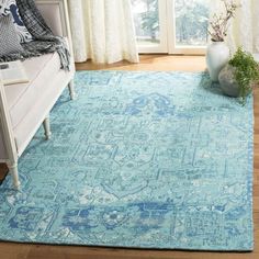 a blue area rug with an ornate design on the top and bottom, in front of a window