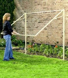 a woman standing in front of a brick building with a soccer goal on the grass