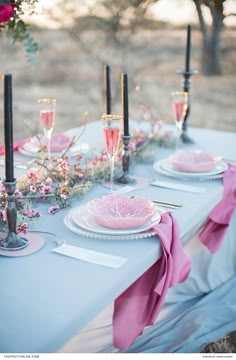 the table is set with pink plates and silverware for an elegant dinner or bridal party