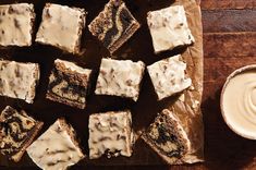 brownies with white frosting on a cutting board next to a cup of coffee