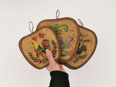 This is a set of 3 apple-shaped graduated size wood trivets. Each one has a layer of cork decorated with different images of folk art roosters. They are vintage 1970s or 80s and made in Taiwan. Paint Cork, Colorful Rooster, Wood Trivets, Dutch Style, Pennsylvania Dutch, Sustainable Style, Search And Rescue, Folk Art Painting, Trivets