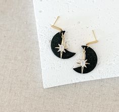 Welcome to Katie Collins Design Co. Get ready to star gaze with these gorgeous gold and black crescent moon star dangle earrings. Classic, fashionable and trendy, these dangles feature 18k gold plated brass, opal glass and cubic zirconia stars. Attached to shimmery black moons, these earrings together with dainty gold bar earrings posts. Neutral enough to wear with almost anything in your wardrobe, these earrings are sure to turn a lot of heads! Truly one-of-a-kind, all of my earrings are lovingly handmade by me with extremely lightweight polymer clay and nickel free earring posts. I also offer FREE shipping on all orders over $35 as well as a FREE gift with purchase! DETAILS * Handmade of polymer clay. * 18k gold plated brass earring posts with brass, glass and cubic zirconia charms * 1.7 Collins Design, Black Crescent Moon, Star Gaze, Gold Star Earrings, Moon Gold, Gold Bar Earrings, Earrings Classic, Nickel Free Earrings, Celestial Jewelry