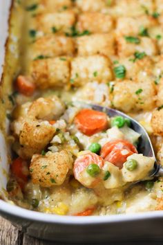 a casserole dish filled with chicken, vegetables and bread croutons on a wooden table