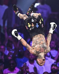 a man with tattoos on his body doing a handstand in front of an audience