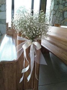 a bouquet of baby's breath sitting on top of a wooden bench next to a window