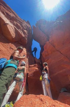 two people climbing up the side of a rock formation, with one person reaching for something