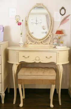 a white dressing table with a mirror and stool