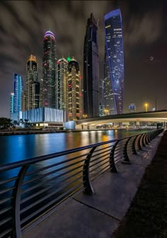 the city skyline is lit up at night by the water with its lights reflecting off