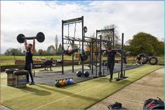 a group of people doing exercises in the park with barbells and squats