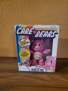 a pink care bears toy sitting on top of a wooden table