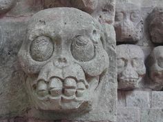 a stone lion head on the side of a building with many smaller heads behind it