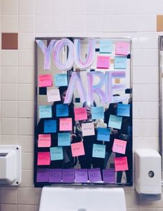 a mirror with post it notes attached to the side of it in front of a urinal