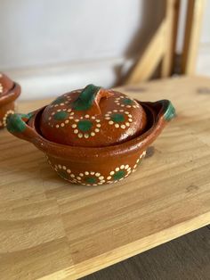 two brown and green pots sitting on top of a wooden table next to each other