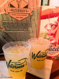 two drinks sitting on top of a table next to a sign that says waterman's fresh local seafood