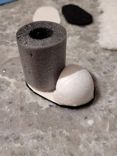 two rolls of toilet paper sitting on top of a white and black object next to each other