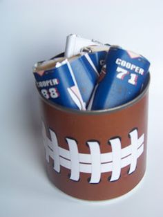 a football themed can holder filled with beer cans and paper towels on a white surface