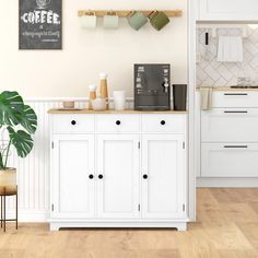 a kitchen with white cabinets and wooden flooring next to a wall mounted coffee maker