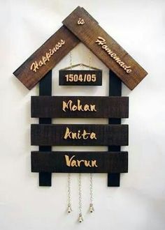 a wooden house sign hanging from the side of a wall with three names on it