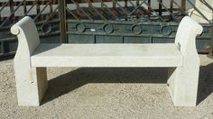 a cement bench sitting in front of a gate with iron bars on the top and bottom