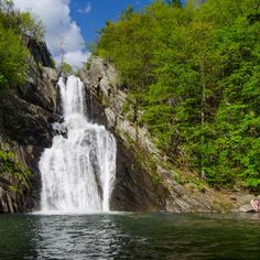 a waterfall with people swimming in the water