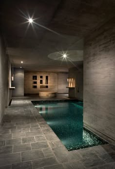 an indoor swimming pool in a house with stone flooring and walls, surrounded by lights