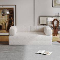 a white couch sitting in a living room on top of a hard wood floor next to a lamp