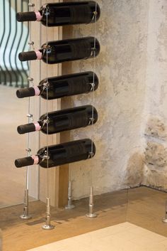 a wine rack with six bottles hanging from it's sides in front of a wall