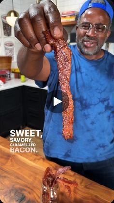 a man holding up a piece of bacon in his hand and pointing it at the camera