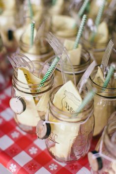 mason jars filled with desserts on top of a red and white checkered table cloth