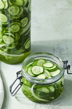 two jars filled with cucumbers sitting on top of a table