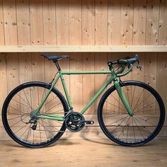 a green bicycle parked in front of a wooden wall with shelves on either side and wood paneling behind it