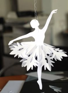 a paper ballerina ornament hanging from a string