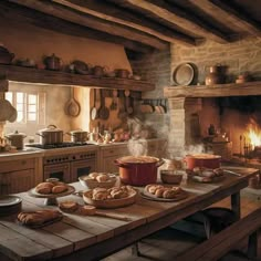 an old fashioned kitchen with baked goods on the table and fireplace in the back ground